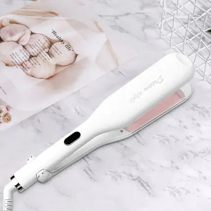 White and pink hair straightener on a marble surface with a blurred background