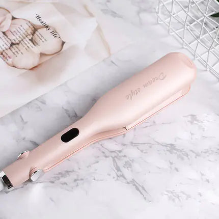 Rose gold hair straightener on a marble surface with a blurred background